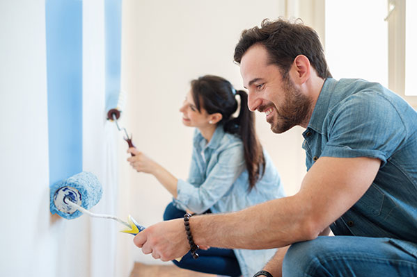 couple painting house wall blue 